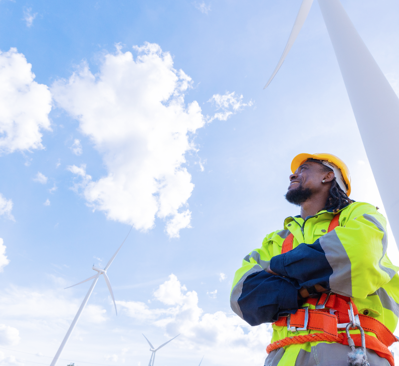 Wind turbine technician looking up at wind turbines